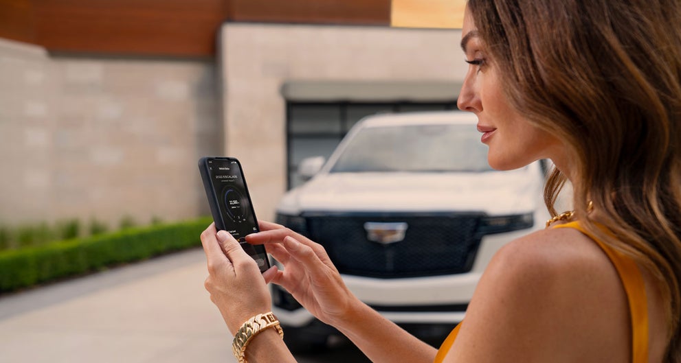 lady checking her mobile with a Cadillac vehicle background | Star Cadillac in Quakertown PA